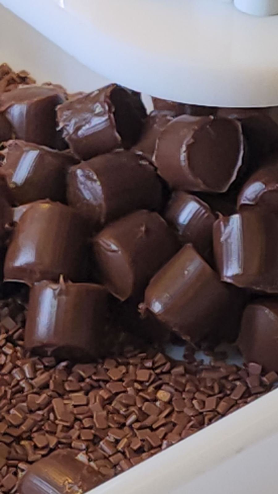 Porções de brigadeiro saindo da máquina sobre o granulado