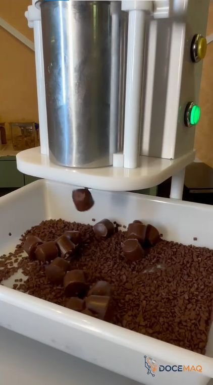 Porção de brigadeiro caindo da máquina direto no granulado